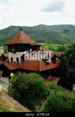 Grande maison traditionnelle avec toit de tuiles rouges à Mokra Gora, en Serbie, entourée de collines boisées. Banque D'Images