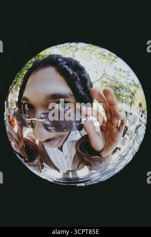 Fish Eye Lens portrait de jeune homme rétro tenant des lunettes de soleil Banque D'Images