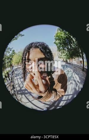 Fish Eye Lens portrait d'un jeune homme avec des cheveux tressés portant des lunettes de soleil dans le parc à la journée ensoleillée Banque D'Images