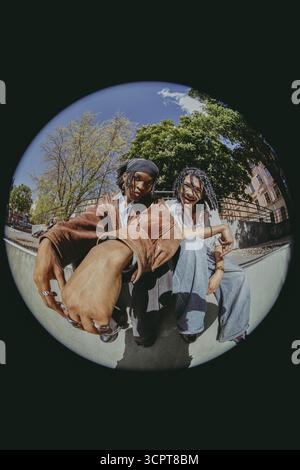 Fish Eye Lens portrait d'amis masculins multiraciaux heureux dans des vêtements rétro assis au parc Banque D'Images