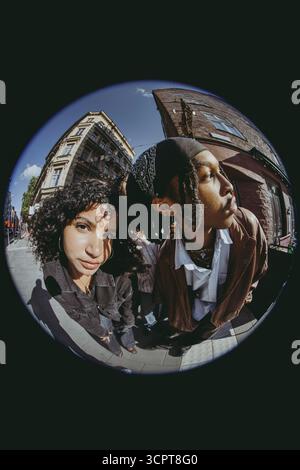 Fish Eye Lens portrait d'une jeune femme debout avec un ami masculin regardant loin Banque D'Images
