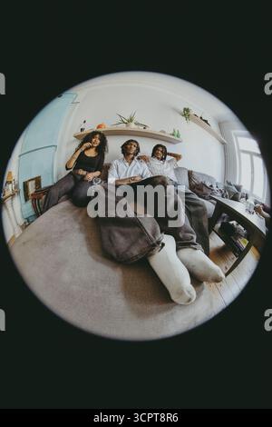 Fish Eye Lens portrait d'amis masculins et féminins multiraciaux assis sur le lit à la maison Banque D'Images