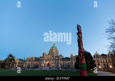 Le soleil se couche sur le mât totémique du savoir sur le terrain des édifices du Parlement de la Colombie-Britannique à Victoria, Colombie-Britannique, Canada. Banque D'Images