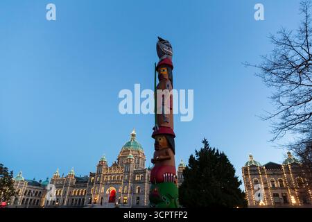 Le soleil se couche sur le mât totémique du savoir sur le terrain des édifices du Parlement de la Colombie-Britannique à Victoria, Colombie-Britannique, Canada. Banque D'Images