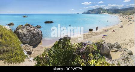 Pittoresque baie de Tsambika avec eau claire, rochers et plage de sable. Les gens apprécient le soleil, un bateau en arrière-plan, une végétation luxuriante, la plage de Tsambika, Banque D'Images
