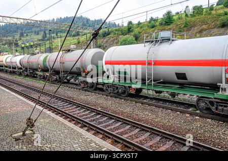 Un train de marchandises industriel avec des wagons-citernes transportant des marchandises liquides est stationné sur des voies ferrées dans une station de montagne Banque D'Images