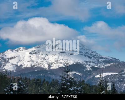 Pic de montagne enneigé sous ciel bleu - vue horizontale d'une montagne majestueuse et enneigée sous un ciel bleu vif avec des nuages blancs, vu ci-dessus Banque D'Images