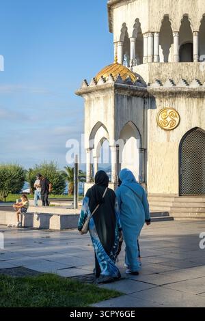 Deux femmes musulmanes marchant devant la tour de l'horloge historique à Batoumi, Géorgie Banque D'Images