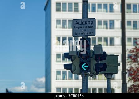 Le pôle montre le signal de flèche gauche qui s'allume en vert tandis que le texte d'avertissement laengere Rotphasen BEI feuerwehreinsatz signifie des phases de lumière rouge plus longues pendant Banque D'Images
