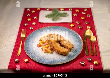Salade de poisson frit et de pommes de terre sur un napperon rouge festif pour une tradition de dîner de vacances Banque D'Images