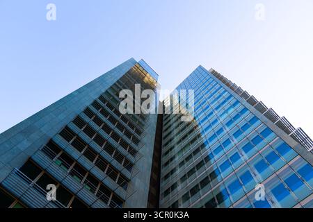 Tour résidentielle moderne de grande hauteur avec façade métallique réfléchissante et lignes géométriques sur un ciel bleu clair Banque D'Images