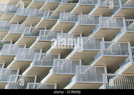 Architecture résidentielle moderne avec balcons répétitifs et façade géométrique sous fond de ciel bleu clair lumineux Banque D'Images