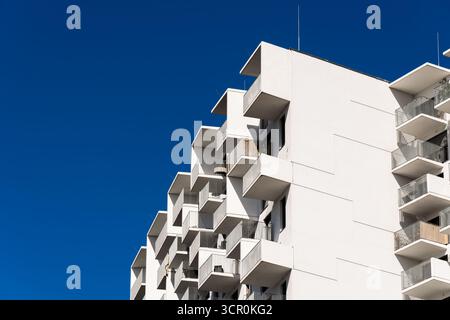 Architecture résidentielle moderne avec balcons répétitifs et façade géométrique sous fond de ciel bleu clair lumineux Banque D'Images