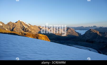 Le soleil se lève sur le glacier des pers, illuminant la glace et les montagnes de la chaîne de la Bernina. Une matinée sereine dans les Alpes suisses révèle le magnifique paysage de Graubunden. Banque D'Images