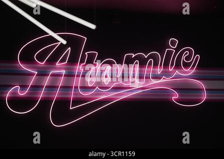 L'enseigne au néon affiche le mot Atomic dans une lueur rose vif sur un fond noir élégant dans un cadre urbain la nuit Banque D'Images