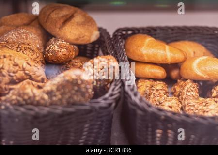 Des petits pains chauds et des pâtisseries variées sont superbement disposés dans des paniers d'une boulangerie locale. Les arômes délicieux accueillent les clients du matin en appréciant leur t Banque D'Images