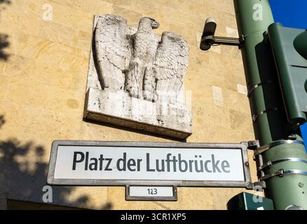 Panneau de rue 'Platz der Luftbrücke' avec sculpture historique d'aigle en arrière-plan, près de l'ancien aéroport Tempelhof de Berlin. Banque D'Images
