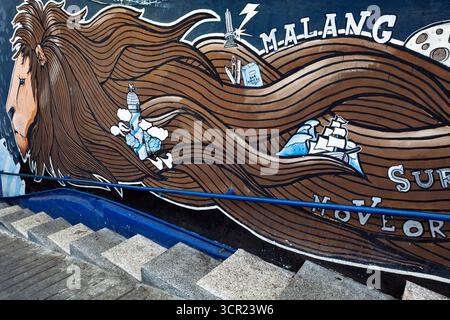 Malang, Indonésie - 12 juillet 2018 : escaliers avec murale sur la rue du village des maisons bleues Kampung Biru Arema. Endroit populaire à visiter pour la marche en ville Banque D'Images