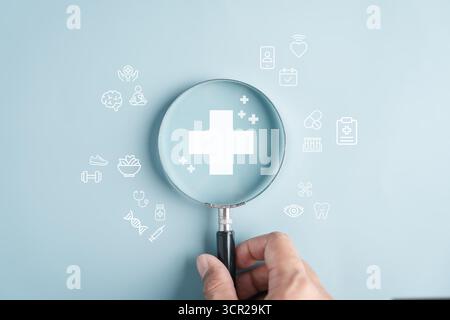 Concept d'assurance médicale de soins de santé avec la main tenant la loupe et les icônes de santé Banque D'Images