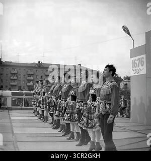 Un ensemble de danse folklorique pour jeunes en costumes traditionnels se produit sur une scène extérieure décorée des armoiries de la ville et des dates d'anniversaire (1676-1985) lors d'une célébration de la Journée de la ville à Sloviansk, en RSS d'Ukraine. Cette série dynamique de photographies en noir et blanc datant de 1985 capture à la fois une programmation formelle et le mouvement énergique de la danse, mettant en valeur la vie culturelle vibrante d'une ville soviétique et symbolisant l'expression artistique joyeuse du Donbass paisible lors d'un festival public Banque D'Images