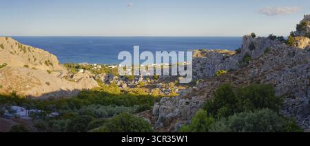 Paysage côtier de Stgna surplombant la mer, encadré par des collines rocheuses et une végétation luxuriante, sous un ciel bleu, Grande Blue Beach, Stegna, Archangelos, R. Banque D'Images