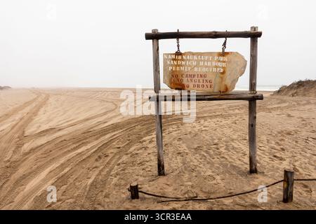 Panneau routier affichant le nom du parc national Namib-Naukluft contre un paysage désertique sous un ciel nuageux, Namibie - 30 août 2025. Banque D'Images