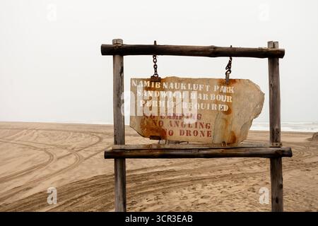 Panneau routier affichant le nom du parc national Namib-Naukluft contre un paysage désertique sous un ciel nuageux, Namibie - 30 août 2025. Banque D'Images