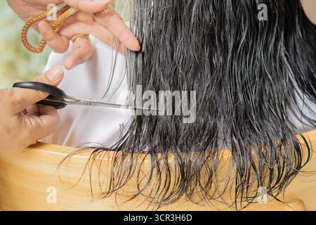 Gros plan d'une femme coupant les cheveux de sa mère âgée à la maison. Concept de style de vie de cheveux gris. Banque D'Images