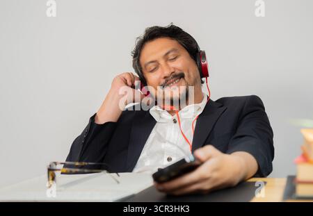 Professionnel masculin détendu avec les yeux fermés en écoutant de la musique pendant une pause du travail au bureau. Mise au point sélective. Banque D'Images