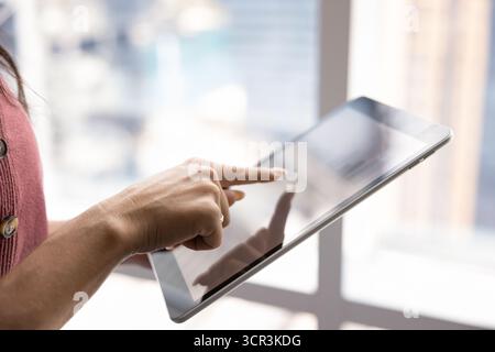 Gros plan, femme analysant des diagrammes ou examinant des données sur tablette Banque D'Images