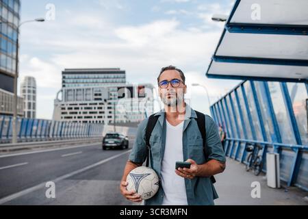 Homme mûr rentrant du travail, SMS sur smartphone. Banque D'Images