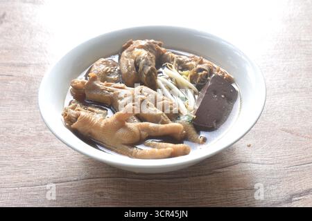 cuisse de poulet bouillie et pieds associent le sang avec le germe de haricot dans une soupe brune aux herbes sur le bol Banque D'Images