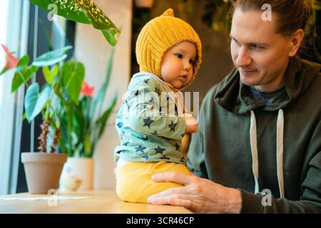 Papa souriant avec un enfant en bas âge dans un café, montrant l'amour et les soins de la famille. Parentalité moderne, temps de qualité, relation père-fils, valeurs de la famille et de la HAP Banque D'Images
