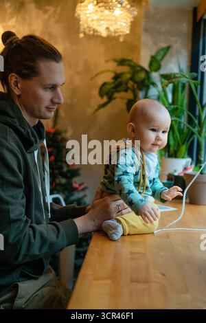 Papa souriant avec un enfant en bas âge dans un café, montrant l'amour et les soins de la famille. Parentalité moderne, temps de qualité, relation père-fils, valeurs de la famille et de la HAP Banque D'Images