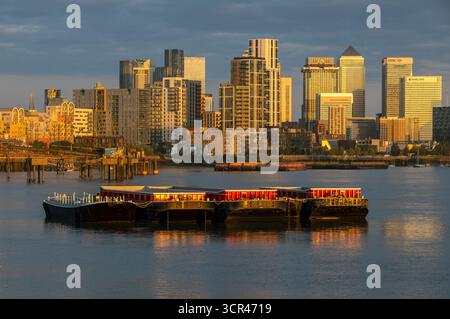 Coucher de soleil doré sur une ville animée avec des bateaux amarrés sur une rivière calme. Canary Wharf, Londres, Royaume-Uni Banque D'Images