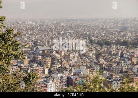 Vue aérienne d'un paysage urbain densément peuplé avec de nombreux bâtiments sous un ciel brumeux. Temple des singes, Katmandou, Népal Banque D'Images