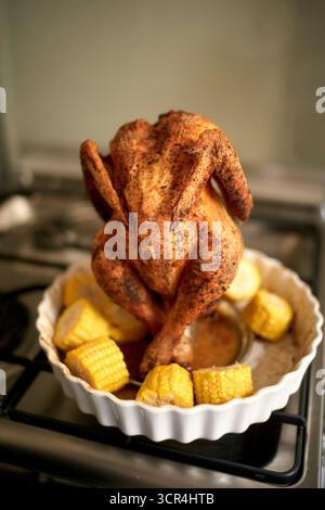 Poulet rôti entier debout avec maïs et pommes de terre dans un plat blanc. Bruxelles, Belgique Banque D'Images