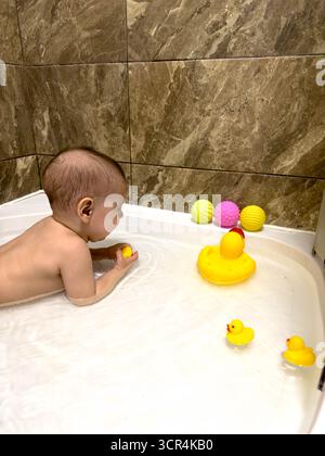 Bébé jouant avec Rubber Ducks dans la baignoire Banque D'Images