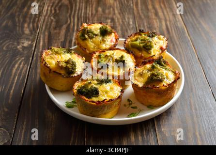 Muffins aux oeufs sains préparés avec des oeufs, du jambon, du brocoli, du fromage sur une table en bois brun. Repas savoureux pour le petit déjeuner ou le déjeuner. Vue rapprochée Banque D'Images