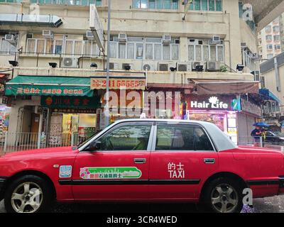 Hongkong, 21 septembre 2025 : un taxi rouge conduisant dans la rue à Hong Kong par jour de pluie Banque D'Images