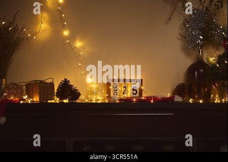 Une scène de vacances chaleureuse avec des jeux de lumières, des cadeaux emballés, des pommes de pin et un calendrier de date sur un buffet en bois sombre. Décor festif crée un ho confortable Banque D'Images