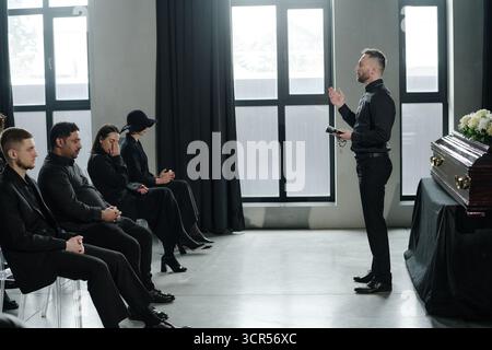 Groupe d'adultes caucasiens et noirs d'âge moyen assistant à la cérémonie funéraire Banque D'Images