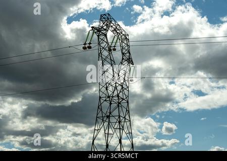 Lignes électriques à haute tension contre un ciel bleu lumineux avec des nuages éparpillés , Puy de Dôme, Auvergne Rhône Alpes, France Banque D'Images