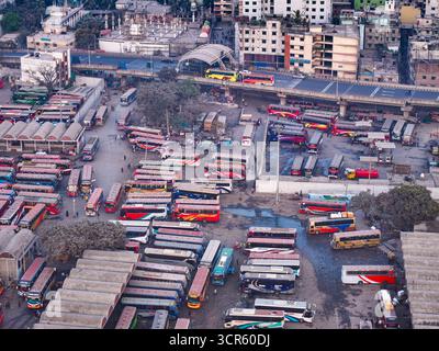 Vue aérienne d'une tapisserie vibrante de bus stationnés étroitement ensemble au terminal de bus de Sayedabad, créant une mosaïque de couleurs contre le paysage urbain, Dhaka, Dhaka Division, Bangladesh. Banque D'Images