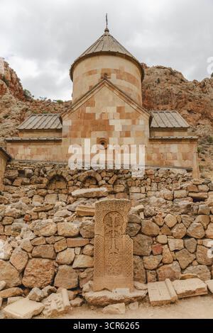 Vue sur la façade en pierre de l'ancien monastère s'élève majestueusement contre les falaises accidentées ocres, un témoignage du temps et de la foi, monastère Noravank, province de Vayots Dzor, Arménie. Banque D'Images
