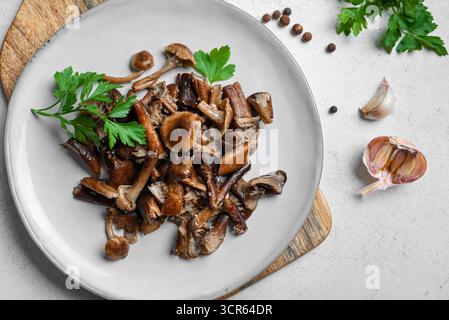 Champignons au miel frits avec ail râpé. Champignons shiitake prêts à manger sur fond de béton blanc, vue de dessus. Banque D'Images