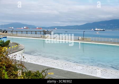 Vancouver, Canada - 15 septembre 2025 : vue panoramique de la piscine Kitsilano avec des nageurs profitant de l'eau, encadrée par un front de mer serein, des montagnes lointaines, et Banque D'Images