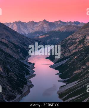Vue aérienne de la vallée de montagne avec un lac au coucher du soleil dans les Alpes Banque D'Images