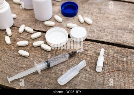 Fournitures médicales, y compris seringue, pilules et flacons sur table en bois avec lumière naturelle Banque D'Images