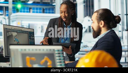 Responsable d'usine photovoltaïque et collègue brainstorming, ajustant les paramètres du système pour maximiser la production d'énergie. Homme parlant avec un collègue, optimisant l'approvisionnement en énergie dans l'usine de panneaux solaires, caméra B. Banque D'Images